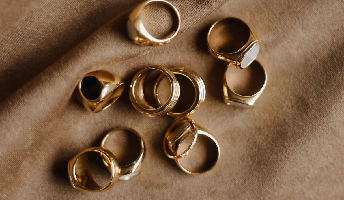 Elegant gold rings beautifully stacked, complementing a personalized gold initial necklace and custom name chains