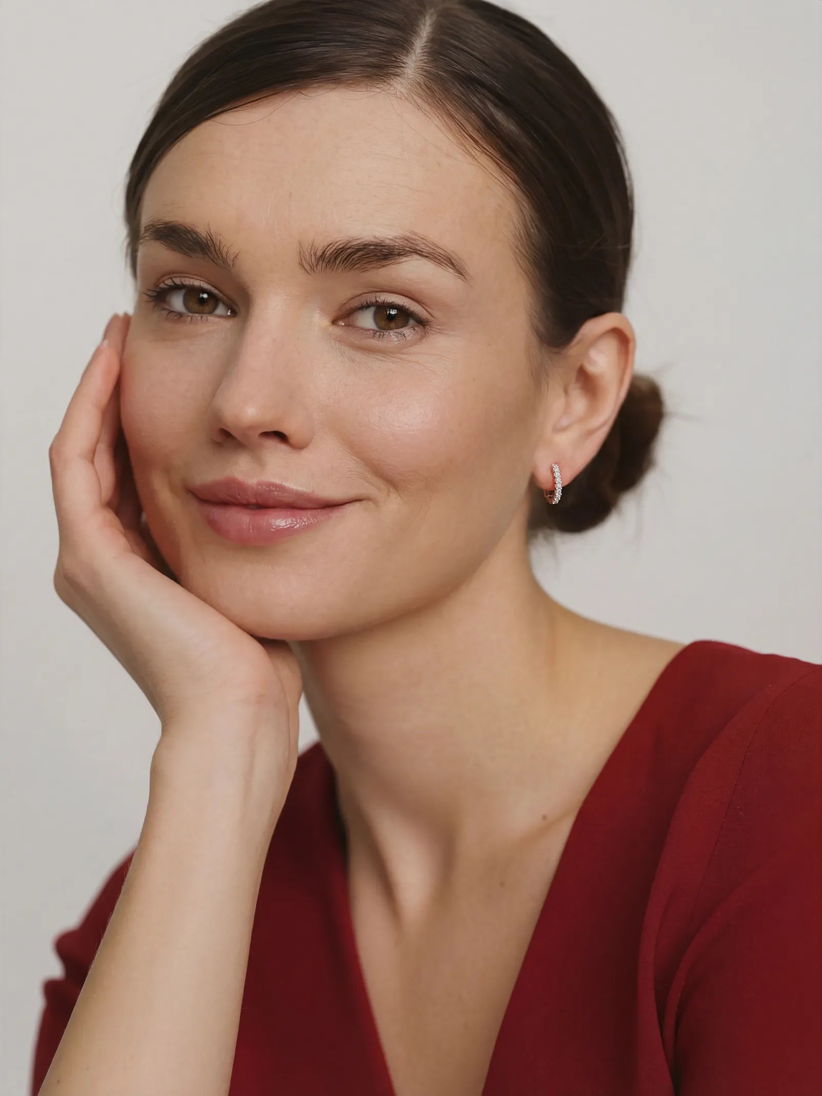 Woman with a soft smile, wearing a red top against a plain background